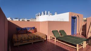 a balcony with a bed and chairs on a roof at La casa de Oasis in Essaouira