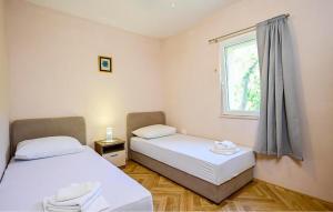 two beds in a room with a window at Stunning Apartment In Janjina With House Sea View in Drače +5 photos