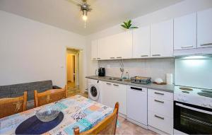 a kitchen with white cabinets and a table with a dining room at Stunning Apartment In Janjina With House Sea View in Drače