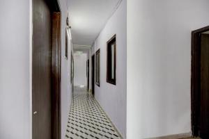 ニューデリーにあるSuper Hotel O Blissbournの白い壁と白と黒のタイルフロアの廊下