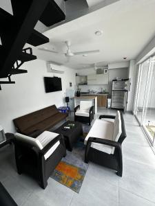 Una sala de estar con un sofá y sillas y una cocina. en Dúplex en Condominio Privado con Piscina, 