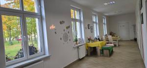 Una habitación con una mesa y sillas amarillas y ventanas. en Studio 2 - Strefa Zen pokoje z klimatem przy parku, en Jelenia Góra
