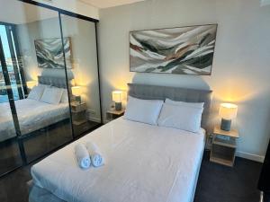 a bedroom with a white bed with two slippers on it at Fortitude Valley Stylish Comfortable Apartment in Brisbane