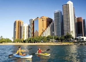 two people in kayaks in the water near a city at Residence Scala in Fortaleza
