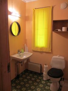 a bathroom with a sink and a toilet and a yellow curtain at VARANGER KITE CAMP in Austertana
