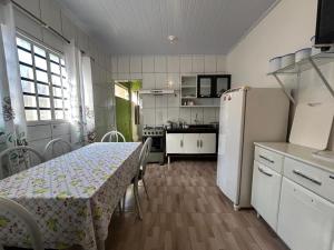 a kitchen with a table and a white refrigerator at casa cristal in Alto Paraíso de Goiás