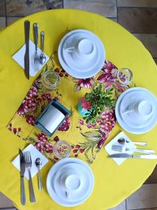una mesa amarilla con platos y utensilios blancos encima en Pousada Refúgio da Serra, en São Thomé das Letras