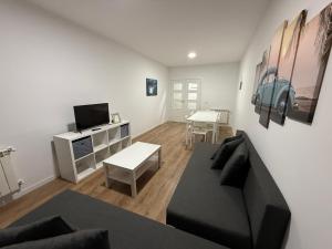 a living room with a black couch and a tv at Vut ILLA PANCHA in Ribadeo