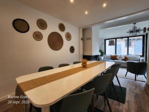 a dining room and living room with a table and chairs at Maison Cosy, proche Reims, La Nichée in Bazancourt