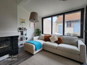 a living room with a couch and a fireplace at Maison Cosy, proche Reims, La Nichée in Bazancourt