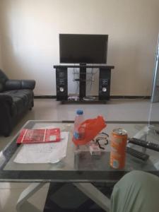 un salon avec une table en verre et une télévision dans l'établissement Hébergement 4 pièces Dakar, à Darou Rhamane