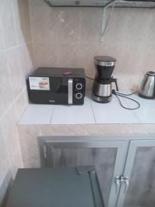 un four micro-ondes assis sur un comptoir à côté d'un mixeur dans l'établissement Hébergement 4 pièces Dakar, à Darou Rhamane