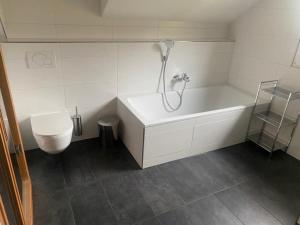 a white bathroom with a tub and a toilet at The Laerch in Hohentauern +23 photos