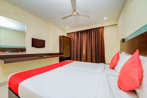 ハイデラバードにあるHotel O Kachiguda Railway Stationの大きな白いベッドと赤い枕のある寝室