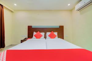 ハイデラバードにあるHotel O Kachiguda Railway Stationの大きな白いベッドと赤い枕のある寝室