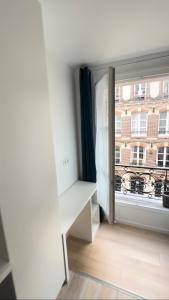 a room with a window and a desk and a building at Coliving Marais in Paris
