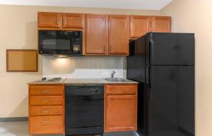 eine Küche mit einem schwarzen Kühlschrank und Holzschränken in der Unterkunft Extended Stay America Suites - McAlester - Hwy 69 in McAlester
