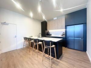 a kitchen with a black island with stools and a counter at Love Our Loft in Napier
