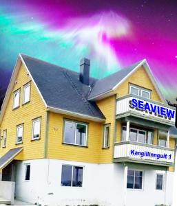 a yellow house with a sign in front of it at Seaview Greenland 