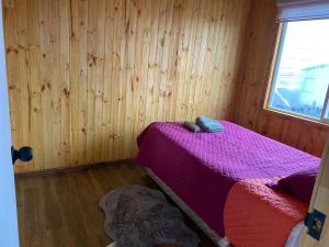 1 dormitorio con cama morada en una pared de madera en Cabañita Ten Ten Vilú, en Quellón