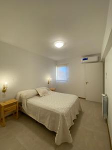 a white bedroom with a bed and a window at Departamento Capital San Juan in San Juan