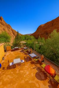 a patio with tables and chairs and a fence at Auberge La Fibule Du Dades in Aït Idaïr