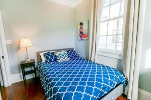 a bedroom with a blue and white bed and a window at Kerlerec Victorian Cottage - Steps to French Qtr. in New Orleans
