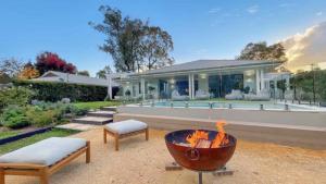 einen Hinterhof mit einer Feuerstelle und einem Haus in der Unterkunft Whitepepper Cottage in Pokolbin