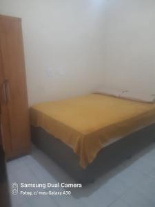 a bed with a yellow blanket on top of it at Casa sobrado in Arraial do Cabo