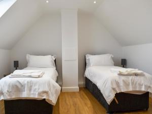 2 łóżka w pokoju z białymi ścianami i drewnianą podłogą w obiekcie Fallow Cottage - Uk33488 w mieście Hadleigh