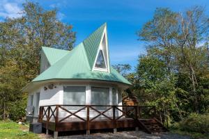 een klein wit huis met een groen dak bij ウィステリア in Teshikaga