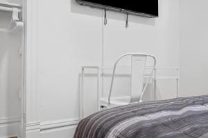 a white chair sitting next to a bed in a room at Pittsburgh Shadyside 1D Stylish and Cozy Private Bedroom with Shared Bathroom in Pittsburgh