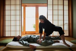 a woman standing on top of a man on a pillow at Shizuka Ryokan Japanese Country Spa & Wellness Retreat in Hepburn Springs