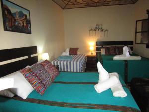 two beds in a room with green sheets at Casa Calvario in Antigua Guatemala