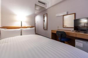 a hotel room with a bed and a desk and a television at Hotel New Saitama in Saitama