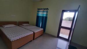 a bedroom with two beds and a window at Riddhi Homestay in Dahmi