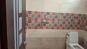 a bathroom with a toilet and a tiled wall at Riddhi Homestay in Dahmi