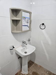 a white bathroom with a sink and a mirror at Eastern Breeze in Hainamosa