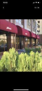 Un edificio con toldos rojos en una calle con arbustos. en The Grand Classic Apartment, en Tashkent