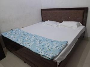 a bed with white sheets and a blue blanket on it at Vrindavan Homestay in Vrindāvan +3 photos