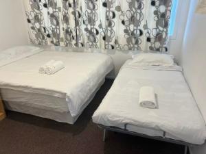 two beds in a small room with white sheets at 4 Beds Including 1 Sofa Bed in 1 Bedroom plus1 Lounge in Auckland