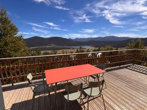 a red table and chairs on a deck with a view at Chalet moderne 100m² pour 8 pers - Vue sur le lac - FR-1-758-44 in Les Angles
