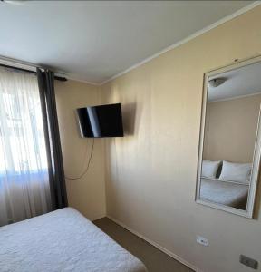 a bedroom with a tv on the wall and a mirror at Hostal Abrazo de Maipu in Santiago