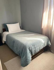a bed sitting in a bedroom with a window at Hostal Abrazo de Maipu in Santiago