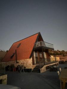 une petite maison avec un toit rouge et une vitre dans l'établissement Umm Aljulud Cottages, à Ajloun