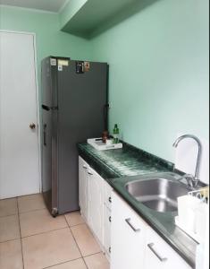 a kitchen with a sink and a refrigerator at Hostal Abrazo de Maipu in Santiago +19 photos