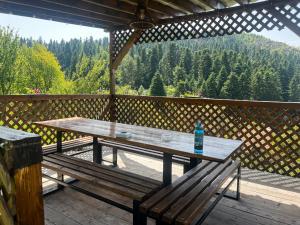 a wooden picnic table on a deck with a bench at Cabana "Tăul Brazi" in Roşia Montană