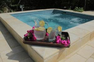 a tray with drinks and flowers next to a swimming pool at Karana Suite One Bedroom - K3 in Long Bay Hills