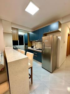 パリョサにあるApartamento NOVO e moderno em palhoçaのキッチン(青いキャビネット、ステンレス製の冷蔵庫付)