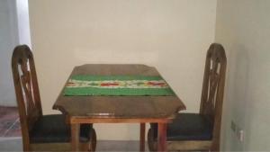 a wooden table with two chairs with a green table cloth on it at Lovely Garden Veiw with Queen Seize Bed in Portland in Port Antonio